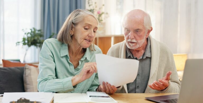 home-laptop-and-elderly-couple-with-documents
